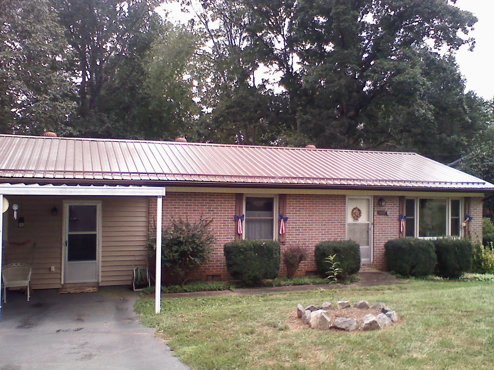 Bronze metal roof and carport on a brick ranch home — Roof Repair work by our crew in Hastings